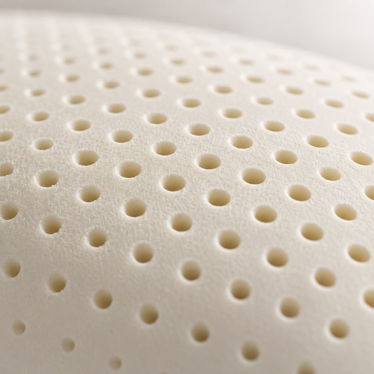 Close-up macro of the precision pinhole perforations across a natural latex pillow surface