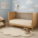 Kids Latex Mattress — the cot-size quilted latex mattress in an oak cot, sky-and-clouds nursery