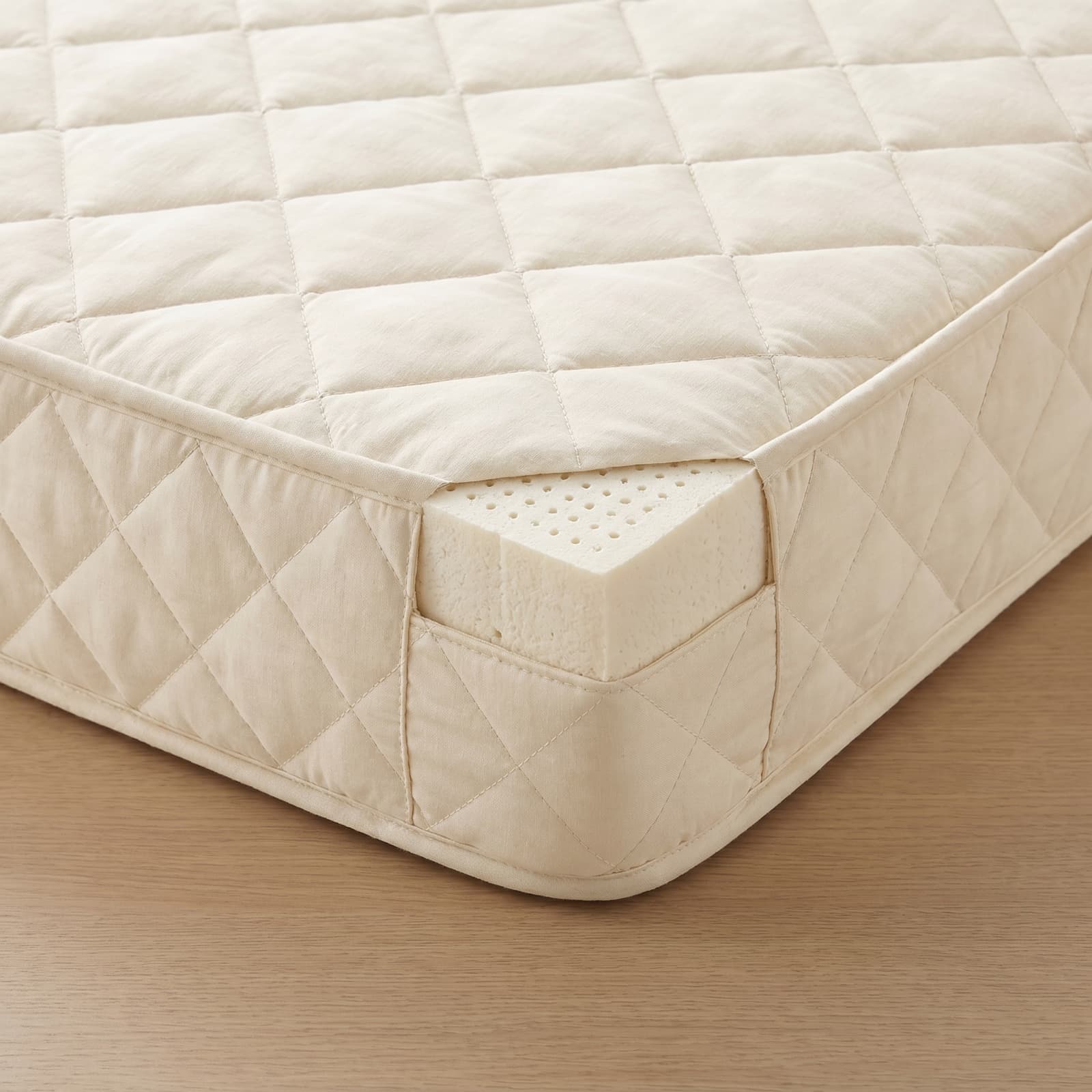 Close-up of the quilted cover and natural latex core of the kids mattress